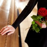 woman with red roses and coffin at funeral